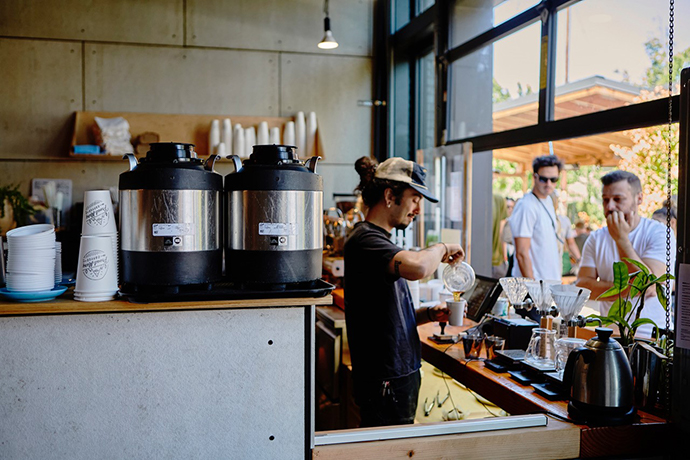 Barista pouring coffee into paper cup at a Proud Mary cafe location.