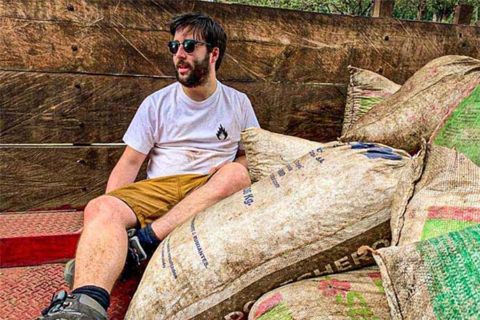 A man sitting next to several coffee sacks.