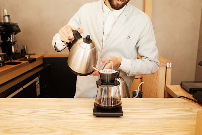 Barista pouring coffee through a filter.