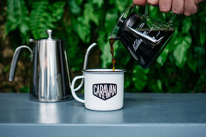 Coffee being poured into a Caravan white cup.