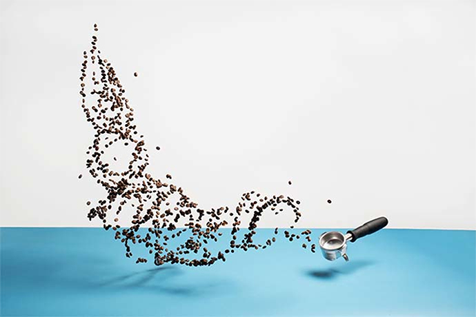 Coffee beans and portafilter on a blue and white background.