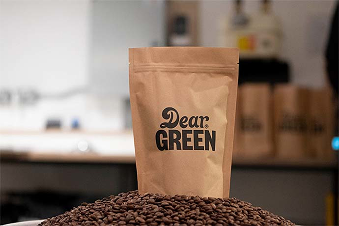 Dear Green coffee bag sitting on top of coffee beans.