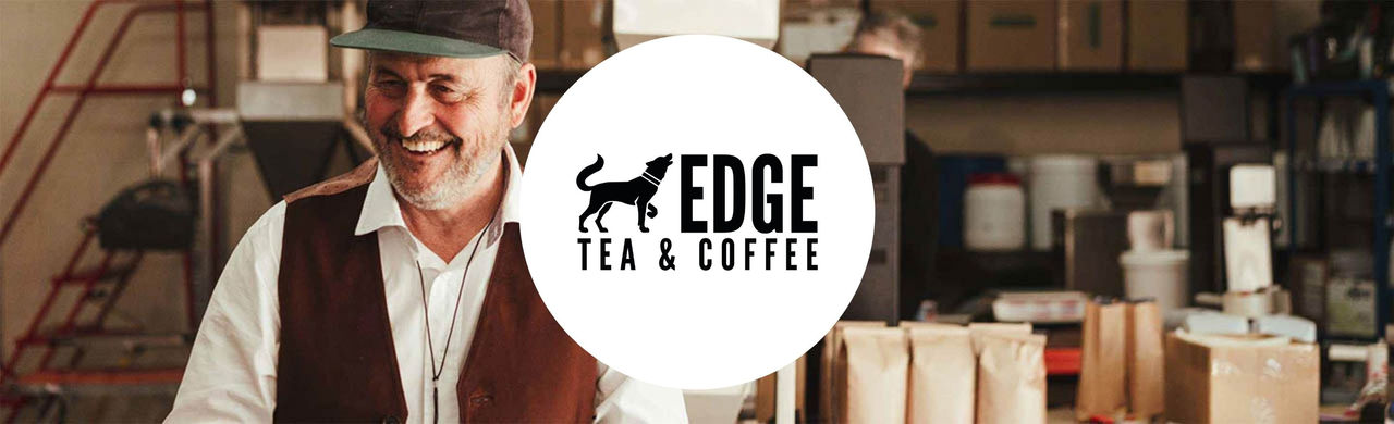 Edge logo and man smiling in front of a coffee machine and coffee bags.