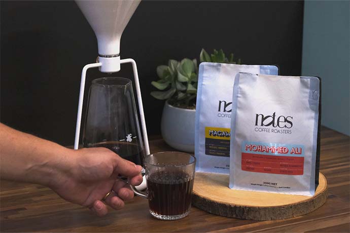 Macaw Espresso and Mohammed Ali coffee bags next to a coffee cup.