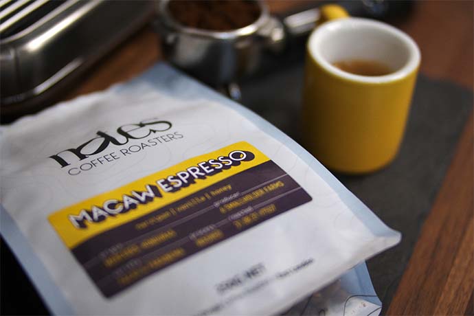 Macaw Espresso coffee bag next to a yellow coffee cup.