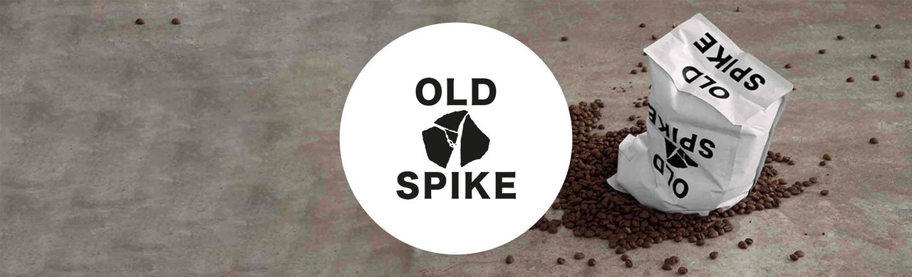 Old Spike logo and a coffee bag on top of spilled beans in the background.