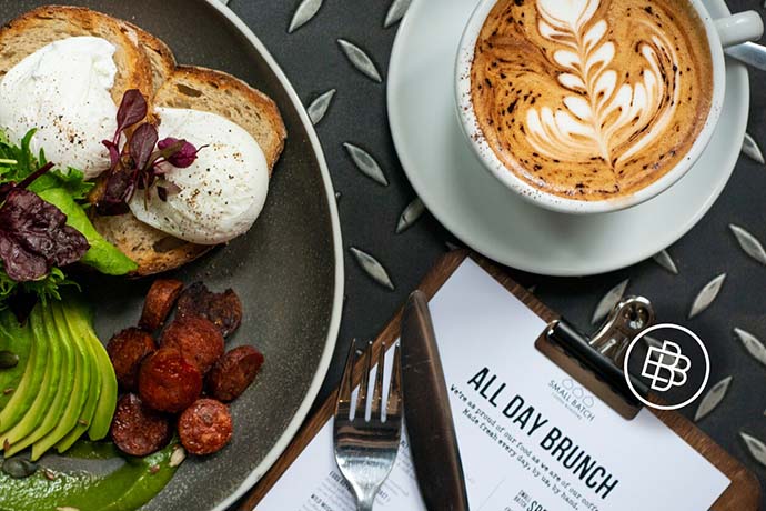A coffee cup and breakfast dish beside an 'ALL DAY BRUNCH' menu. 