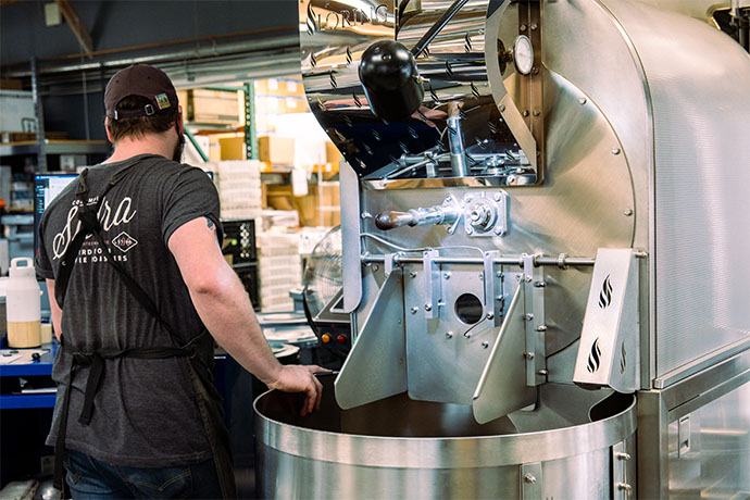 Roasting staff standing in front of Loring roasting machine.