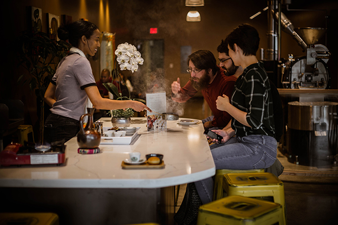 People enjoying a cupping experience with a barista at a Boon Boona cafe.