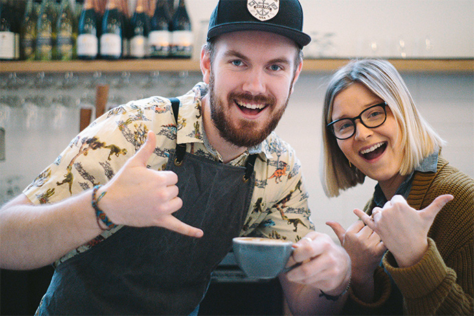 Camber staff doing the "hang ten" hand gesture while holding a cup of coffee.