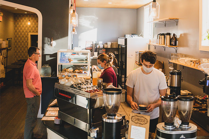 Deeper Roots cafe with baristas preparing coffee and serving food.