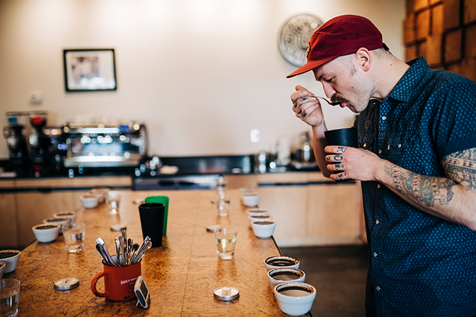 Multiple coffees being cupped with a cupping spoon by a barista.