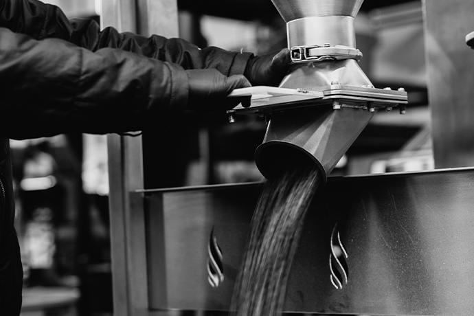 Black and white shot of a coffee bean hopper being emptied.