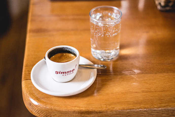 A shot of espresso in a small Gimme! coffee cup.
