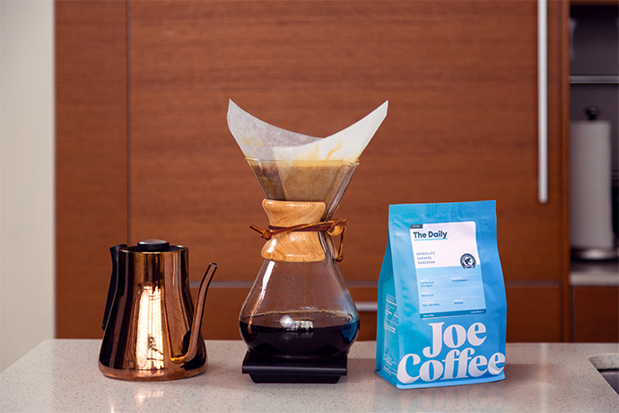 Pourover coffee set-up with 'The Daily' Joe Coffee bag next to a Chemex brewer.