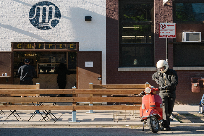 Person getting on their moped outside a Metric cafe location.