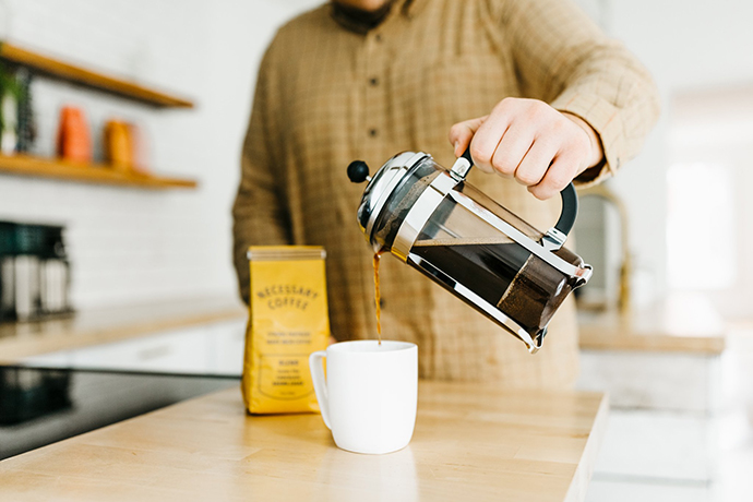 Necessary coffee being poured out of a french press brewer.