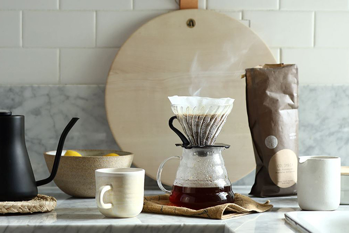 Various coffee brewing equipment in a kitchen with a pourover brewer visibily steaming.