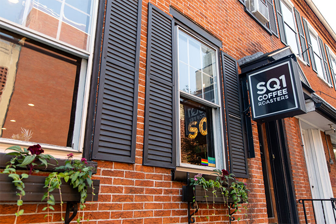 Square One cafe location show its hanging sign and Spanish-style windows.