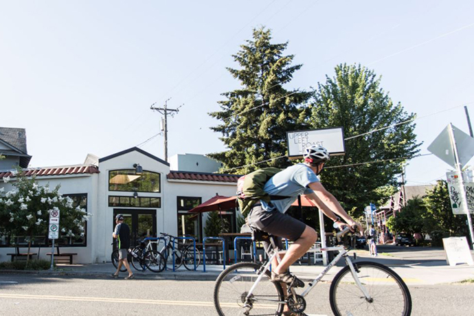Bicyclist riding past a Upper Left Roasters coffee shop.
