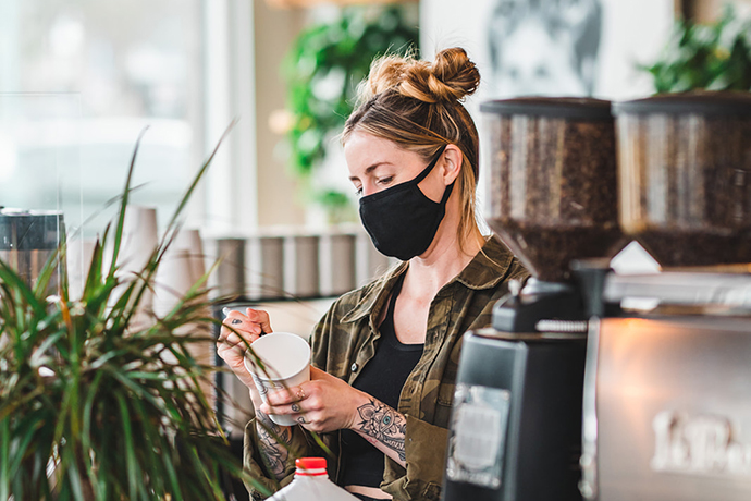 Zoka barista writing on a paper cup at a cafe.